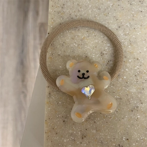 Detailed macro view of a cream resin cartoon bear hair tie with sparkling rhinestone inlay