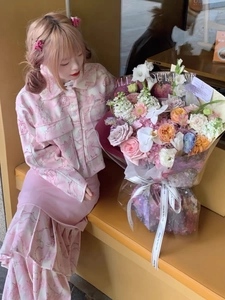 Detailed view of women's two-piece pink floral jacket and pleated skirt with cartoon prints