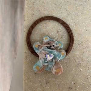 Close-up of marble pattern resin bear charm with a sparkling heart diamond on hair tie