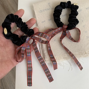 Detail of red and blue checkered ribbon bows on black velvet scrunchies with gold charm