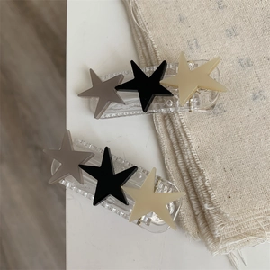 Detail view of two-piece star hair clips with matte finish in grey, black and beige colors