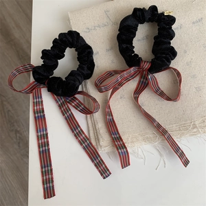 Detail of velvet hair scrunchies with red plaid ribbons for high ponytail styling