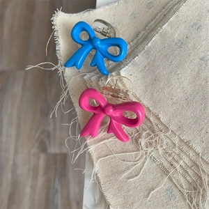 Close-up of pink and blue bow hair claws on textured fabric and wood background