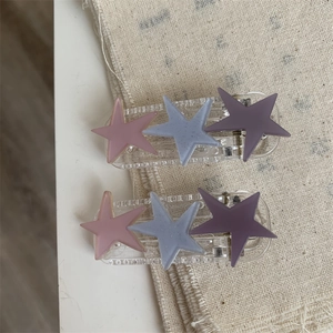 Close-up of star hair clips featuring matte pink, blue, and purple star-shaped ornaments