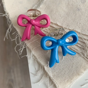 Detailed close-up of pink and blue bow hair clips on a textured white fabric background