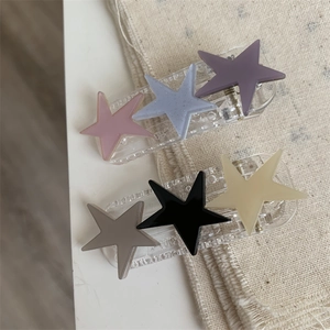 Close-up of matte colorful star hair clips on elegant beige linen fabric background