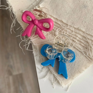 Detail of pink and blue resin bow hair clips on textured fabric background