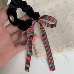 Close-up of velvet hair scrunchie with tartan ribbon and golden metal brand tag