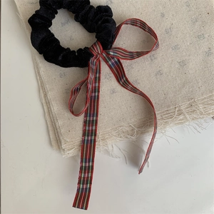 Close-up of a black velvet scrunchie with a red and green plaid ribbon bow detail