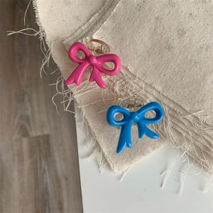 Cute bow hair claw clips in pink and blue colors on minimalist beige fabric background