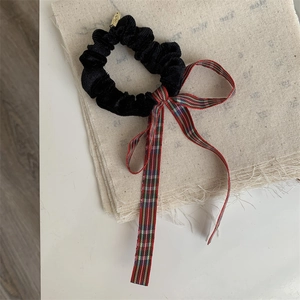 Detail of velvet hair scrunchie with British plaid ribbon and gold metal charm
