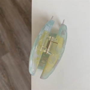 Detail of green and yellow marble acetate hair claw clip with golden metal spring