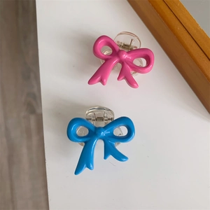 Close-up of pink and blue bow hair claws with transparent bases and metal springs