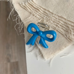 Close-up of a small cobalt blue bow hair claw clip with transparent base and metal spring