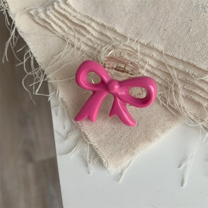Detail of a cute bright pink bow hair claw clip made of glossy resin on linen fabric