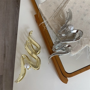 Close-up of gold and silver metallic shark clips with elegant pearl details