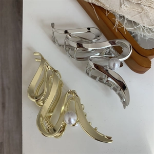 Detail showing gold and silver wavy metal hair claws with elegant pearl embellishment