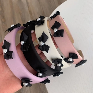 Detail of sponge padded headbands in pastel colors with black bows and pearl hearts