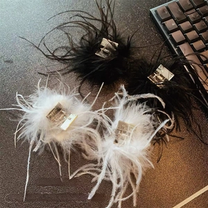 Détail de pinces à cheveux en plumes noires et blanches avec griffe en métal argenté