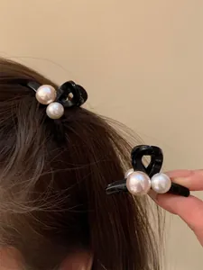 Dettaglio di eleganti fermagli per capelli in resina nera con delicate perle bianche