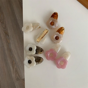 Détail de barrettes à fleurs en acrylique avec base en métal doré de divers coloris