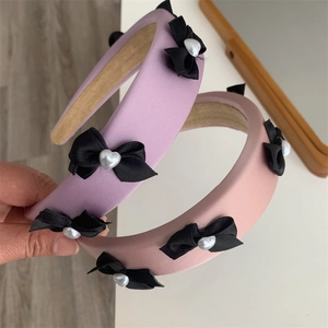 Detail of satin padded headband with black ribbon bows and heart pearl accents