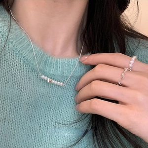 Primo piano della collana con ciondolo a cuore in perle d'acqua dolce su una modella in verde