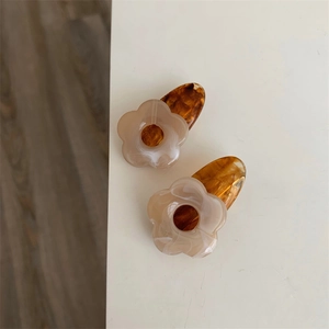 Gros plan de barrettes à fleurs en acrylique avec marbre crème et base en ambre et écaille