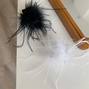 Détail des pinces à cheveux en plumes noires et blanches pour un style élégant et doux