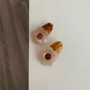 Vue détaillée de deux barrettes à fleurs en résine aux textures ambre et marbre
