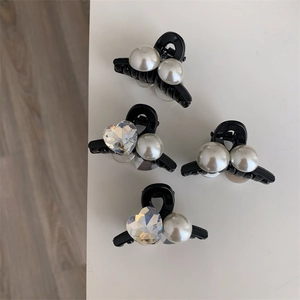 Dettaglio di quattro mini mollette per capelli in resina nera con perle e strass a cuore