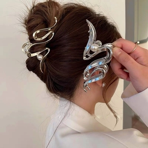 Metallic curved shark hair claw clip with pearl accent shown on a model's hair