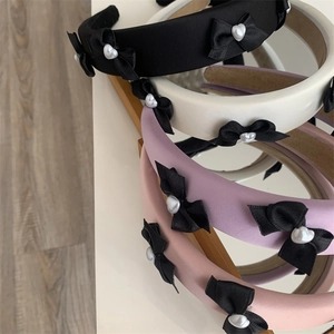 Detail of elegant padded headbands in satin fabric with chic black bows and heart pearls