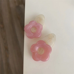 Détail de barrettes à fleurs en acrylique rose avec base en résine effet marbre crème