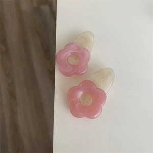 Détail de pinces à cheveux fleur rose avec texture marbre beige en acétate poli