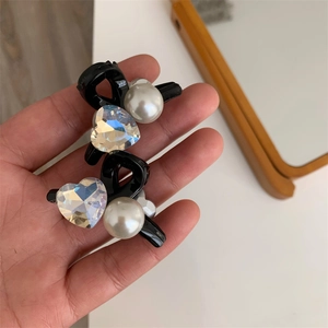 Dettaglio di eleganti fermagli per capelli con cristallo a cuore e perle tenuti in mano
