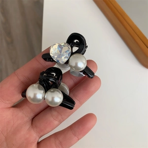 Dettaglio di mini mollette nere con eleganti perle bianche e cristalli a forma di cuore