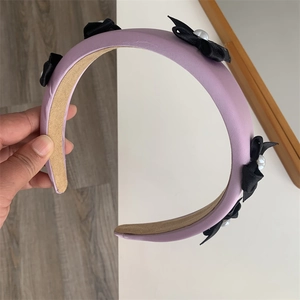 Detail of lavender padded headband with black silk bows and white pearl accents
