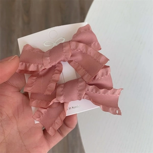 Close-up of pink layered ribbon bow hair clips with textured ruffles on display card