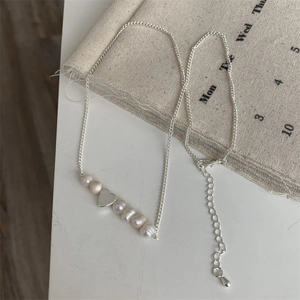 Dettaglio macro di un ciondolo a cuore in argento con perle barocche naturali d'acqua dolce