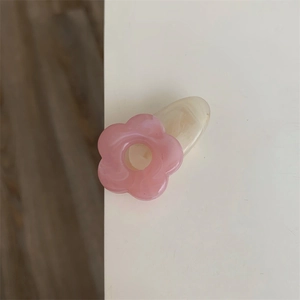 Détail d'une barrette fleur rose en acrylique avec base ovale crème pour femmes