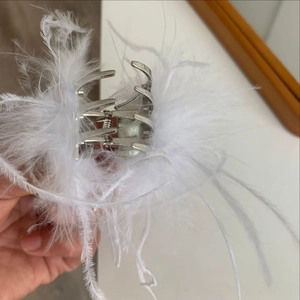 Détail d'une pince à cheveux argentée ornée de plumes blanches moelleuses pour fêtes