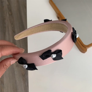 Pink padded sponge headband with black bows and heart pearl detail close-up