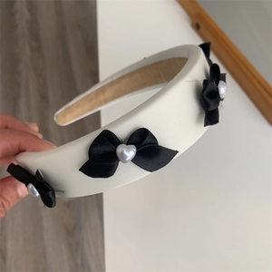 Detail of sponge headband with black silk bows and white heart-shaped pearl accents