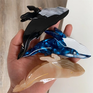 Hand holding acetate blue whale hair claw clips showing marble texture and polished finish