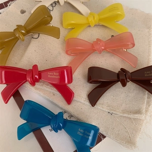 Détail des barrettes à cheveux en forme de nœud coloré avec finition résine mate et texte