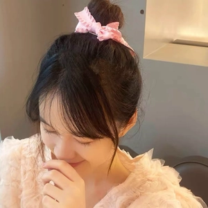 Sweet pink ruffled bow hair clip worn by a model in a cozy indoor setting