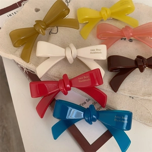 Détail de barrettes à cheveux en résine colorée avec lettrage artisanal fait à la main