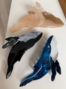 Detailed view of creative whale-shaped acetate hair claws in pink, black, and deep blue