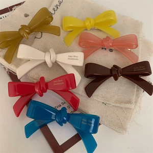 Gros plan de sept barrettes à nœud en acétate coloré avec inscription dorée faite à la main